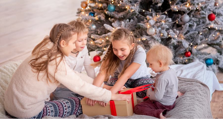 Kids opening a gift in the family room beside a Christmas tree.